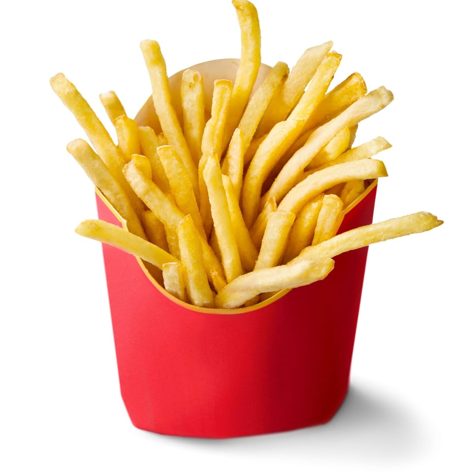 Golden french fries in a red paper container, isolated on a white background.
